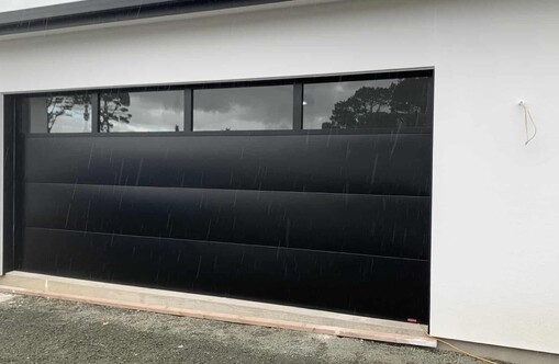 Photo of a sectional garage door with VL Designer windows on the top most panel. Four rectangular window panels with black powder coated steel framing