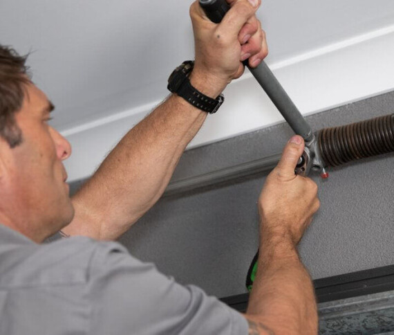 Photo of a Dominator Garage Door repairman tensioning garage door spring