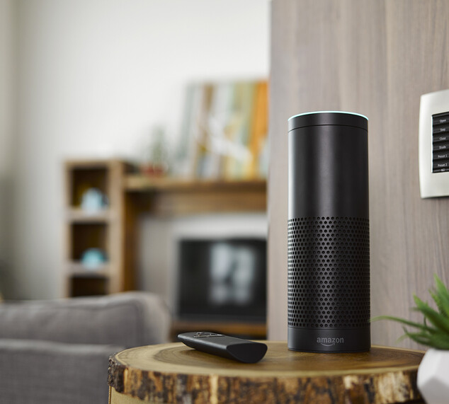 Amazon home speaker set up on a lounge side table beside a remote.