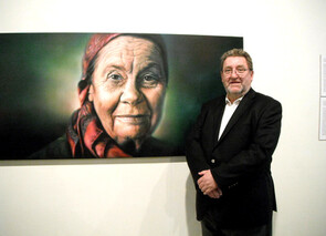 Exhibition curator Brian Easton beside painting of Joan Metge by Sofia Minson