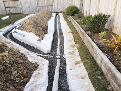 A drainage system on gravel-covered ground with visible pipes.