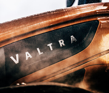 Close-up of the Valtra logo on the metallic bronze bodywork of the S Series tractor, detailed with raindrops and a sleek finish.