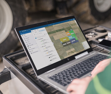Farmer using Trimble Ag Software on a laptop to manage farm operations remotely.
