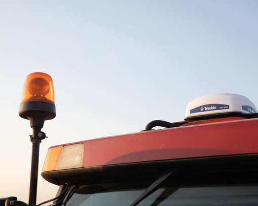 Close-up of a Trimble GPS receiver and beacon on a tractor roof.