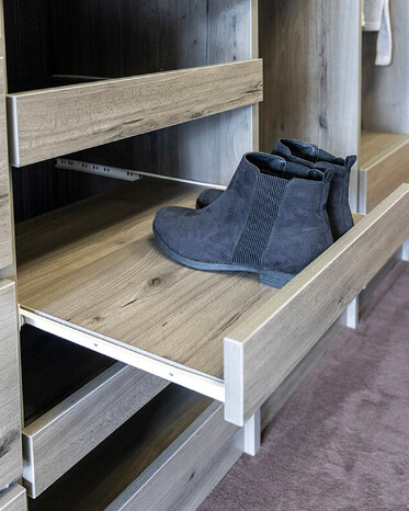 Black shoes on a wardrobe shoe shelf.