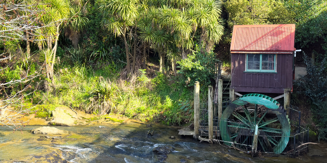 A side view of the river, water wheel and building