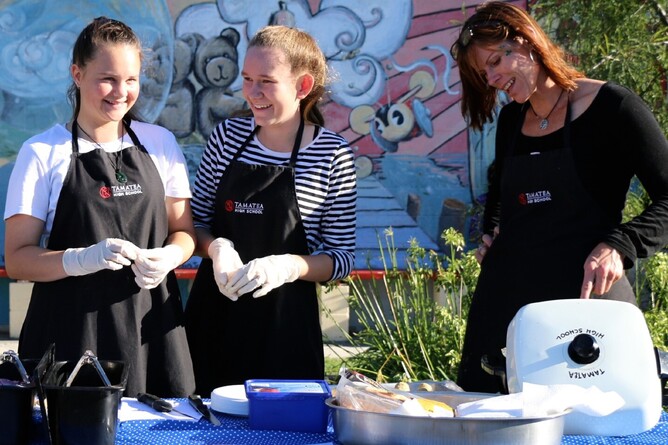 Tamatea High Year 10 students Bailey Hardgrave and Stella Dornan working with teacher Sarah Knight on one of the foodstalls.