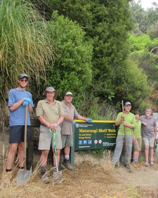 DOC staff and community volunteers standing beside the sign announcing the entry to the Matarangi Bluff Walk