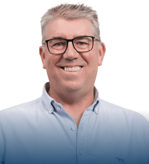 Headshot of Peter, wearing glasses in a light blue shirt, smiling confidently with a plain white background