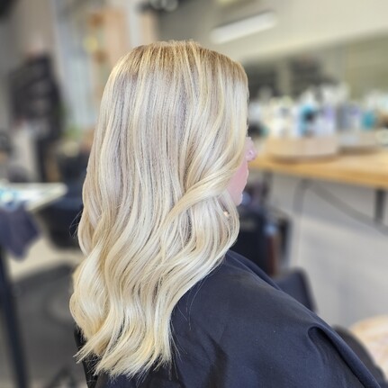 A bright blonde long wavy hair colour and style by Hair by Shiyee.