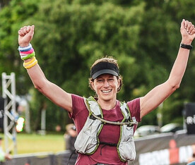 Nicola "Bones" Smallwood, arms raised triumphantly after finishing a race. President of Rotorua Triathlon + Multisport