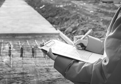Man's hands holding a clipboard looking at construction work