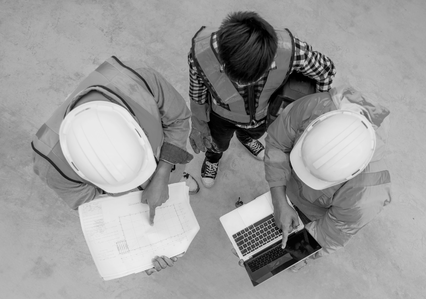 3 men looking at building plans and a laptop