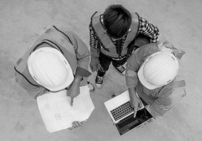 3 men looking at building plans and a laptop