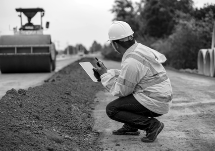 man with walkie talkie looking at roller and piles of dirt