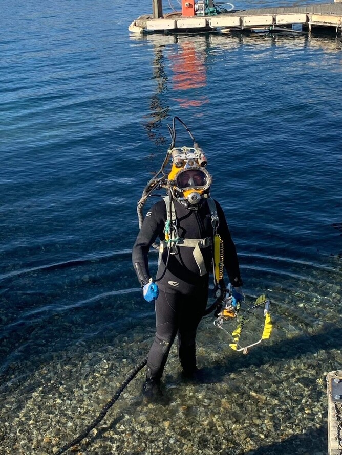 Scuba diver in full diving gear entering the ocean during a dive excursion.
