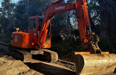 Digger creating trench for irrigation system at an orchard