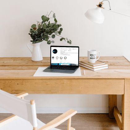 Image of a plant, coffee mug and laptop on a desk. Laptop screen shows social media page for a trades business.