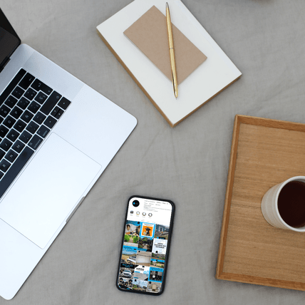 Image of a notebook, coffee cup on a tray, laptop and mobile phone showing social media feed for a trades business.
