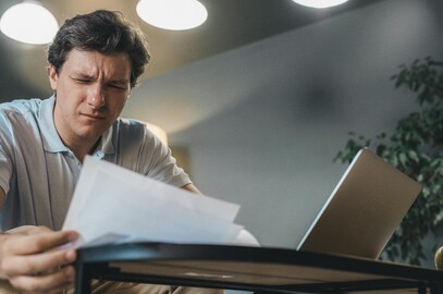 Tradie at kitchen table checking invoices and GST on laptop