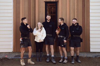 Picture of building team standing in front of a house talking and laughing.