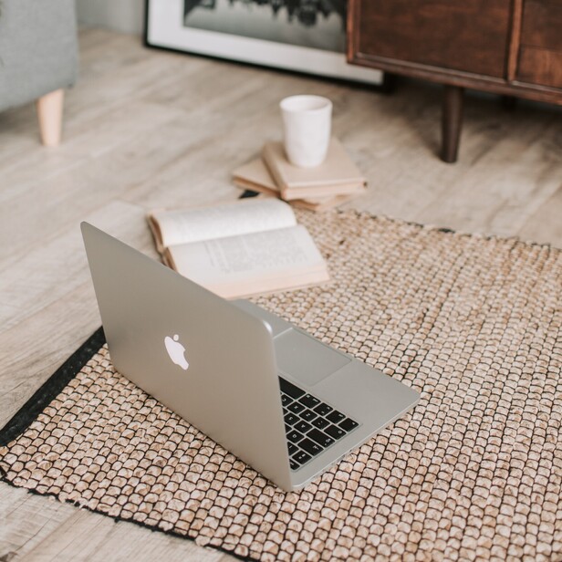 Laptop and books sitting open on the floor on top of reed carpet.