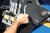 3 - The locking lever is pressed downwards and the front loader securely held in position on the attachment. Then the front loader is raised higher.