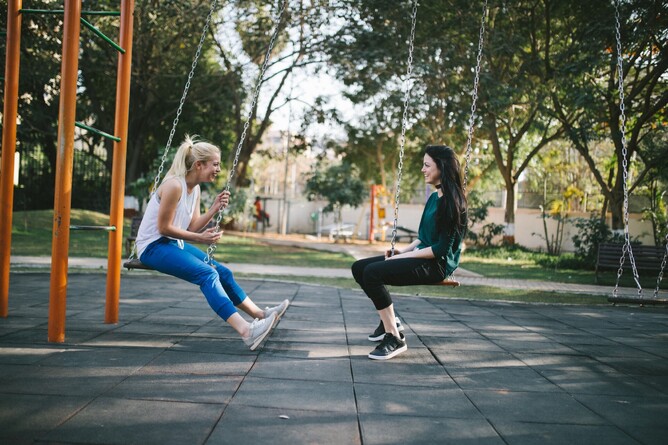 Two women listening to each other on swings
