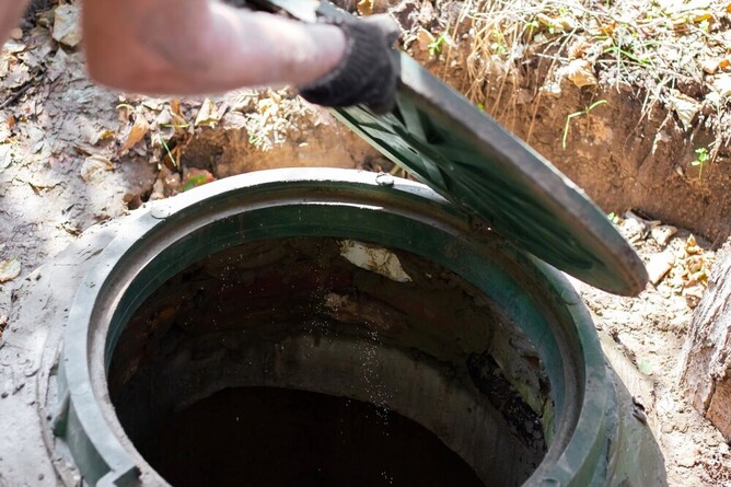 man opening septic tank hatch to inspect