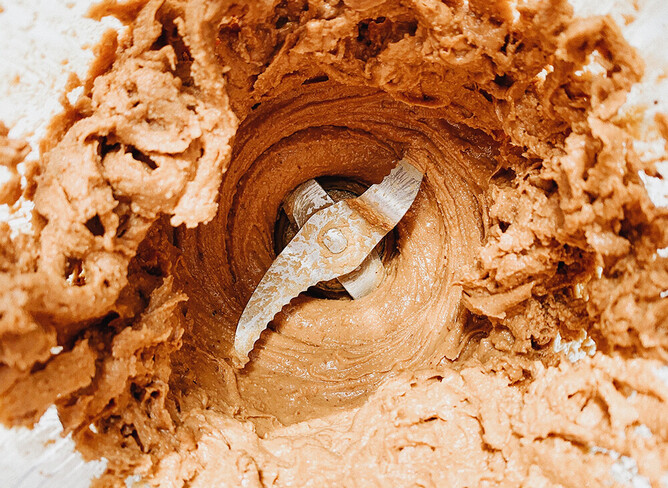 Brown paste being cut up by a metal blade