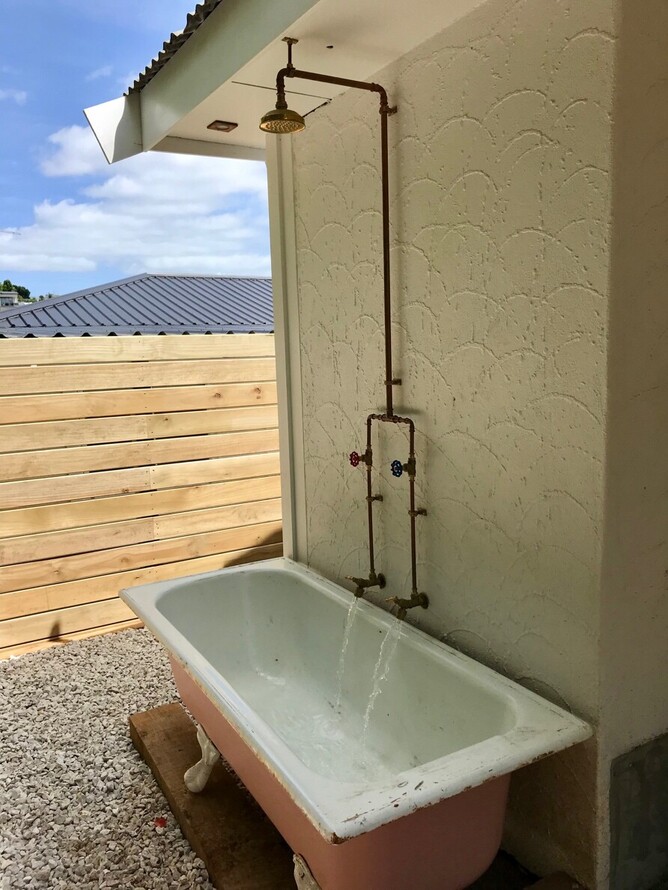 Outdoor shower with copper piping and rustic bath