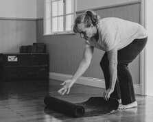 A women rolling out her mat for a Mat Pilates class