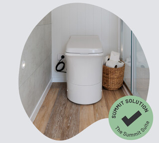 A white incineration toilet fitted into a portable bathroom.