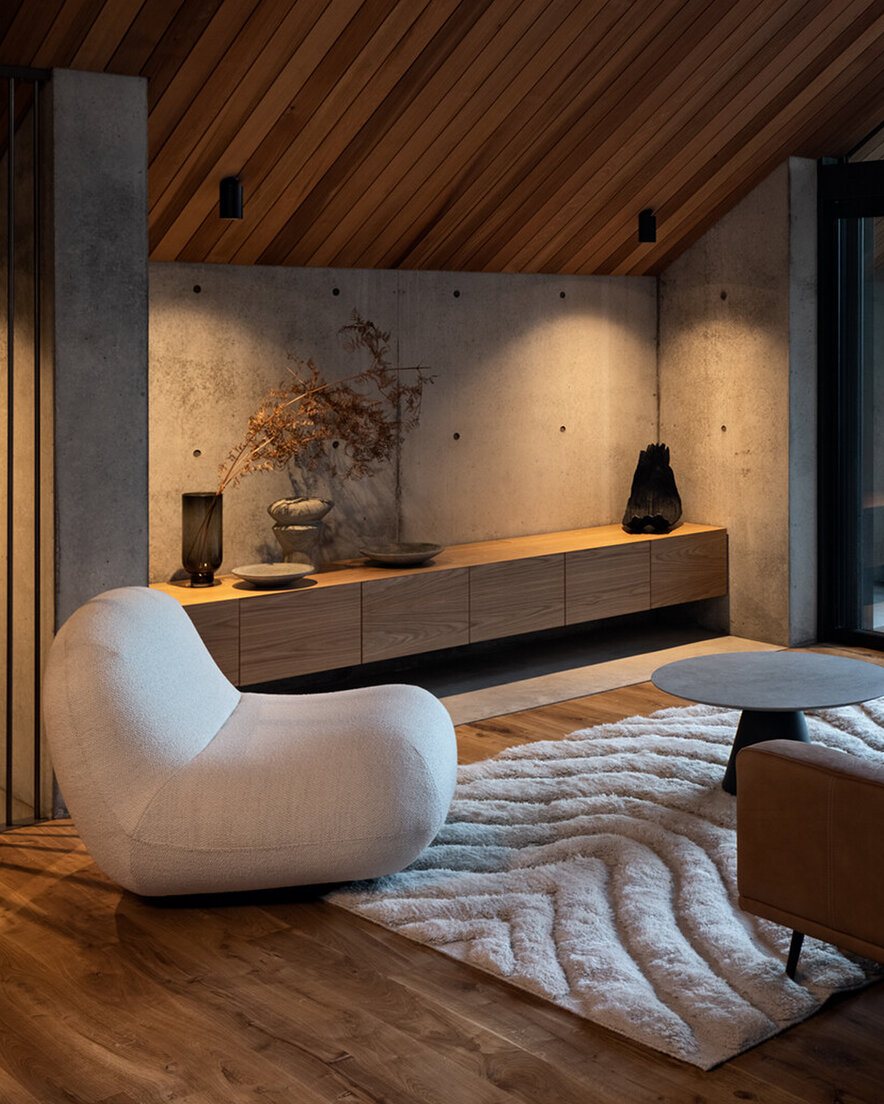 Home interior with wooden floor and ceiling and concrete walls.