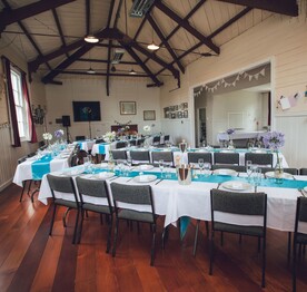 The interior of the Kūaotunu Hall with tables and chairs set up for a wedding