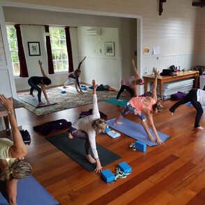 A group of people doing yoga on their yoga mats in the Kūaotunu Hall