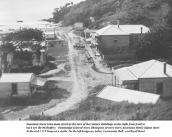 An historic black and white photo showing the lower town main street of Kūaotunu circa 1900