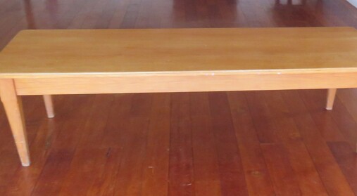 A large rimu table standing on the wooden floor of the Kūaotunu hall