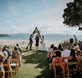 A wedding ceremony being held on the beach at Kūaotunu
