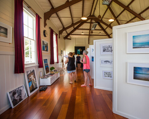 3 people looking at art displayed in the Kūaotunu Hall
