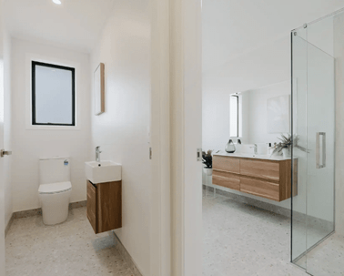 Image of modern neutral toilet and bathroom with timber cabinetry and pale grey tiling in Collinson Street, Pirongia new home, by Waikato residential builders Whitechurch Construction Limited.