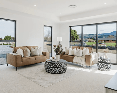 Image of natural light filled lounge with tan lounge suit and modern styling in Collinson Street, Pirongia new home, by Waikato residential builders Whitechurch Construction Limited.