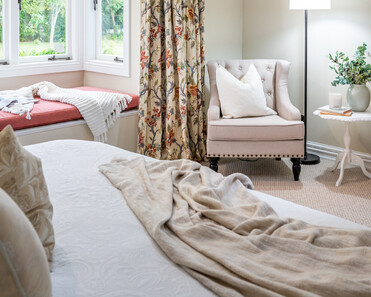 Image of newly renovated master bedroom in sand with floral print curtains and window seat. Renovated by local Te Awamutu residential builders, Whitechurch Construction.
