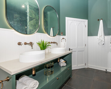 Image of newly renovated heritage bathroom in deep sage & white. Oval mirrors and round basins. Renovated by local Te Awamutu residential builders, Whitechurch Construction.