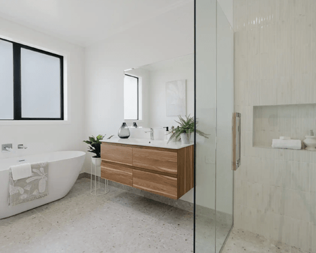 Image of modern neutral bathroom with timber cabinetry, pale grey tiling & glass door shower in Collinson Street, Pirongia new home, by Waikato residential builders Whitechurch Construction Limited.