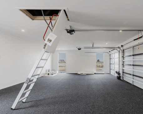 Image of fresh white garage with grey carpet and ceiling access in Collinson Street, Pirongia new home, by Waikato residential builders Whitechurch Construction Limited.