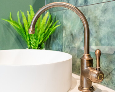 Close up image of copper tap in newly deep sage & white renovated heritage bathroom. Renovated by local Te Awamutu residential builders, Whitechurch Construction.