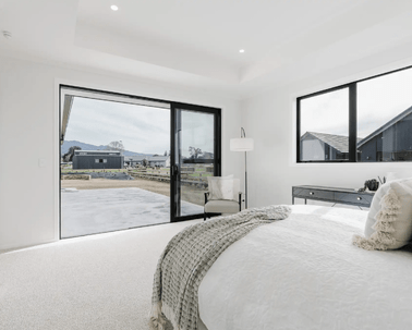 Image of natural light filled master bedroom with neutral styling opening with outlooks in Collinson Street, Pirongia new home, by Waikato residential builders Whitechurch Construction Limited.