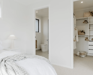 Image of natural light filled master bedroom and glimpse of ensuite and walk in wardrobe in Collinson Street, Pirongia new home, by Waikato residential builders Whitechurch Construction Limited.