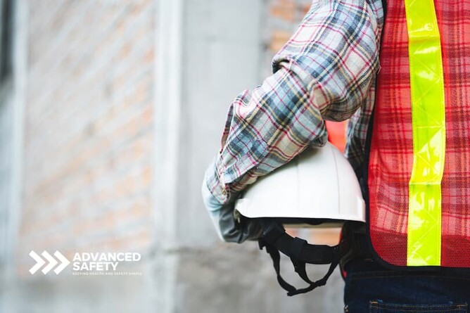 Advanced Safety construction worker wearing hi vis vest and holding a hard hat